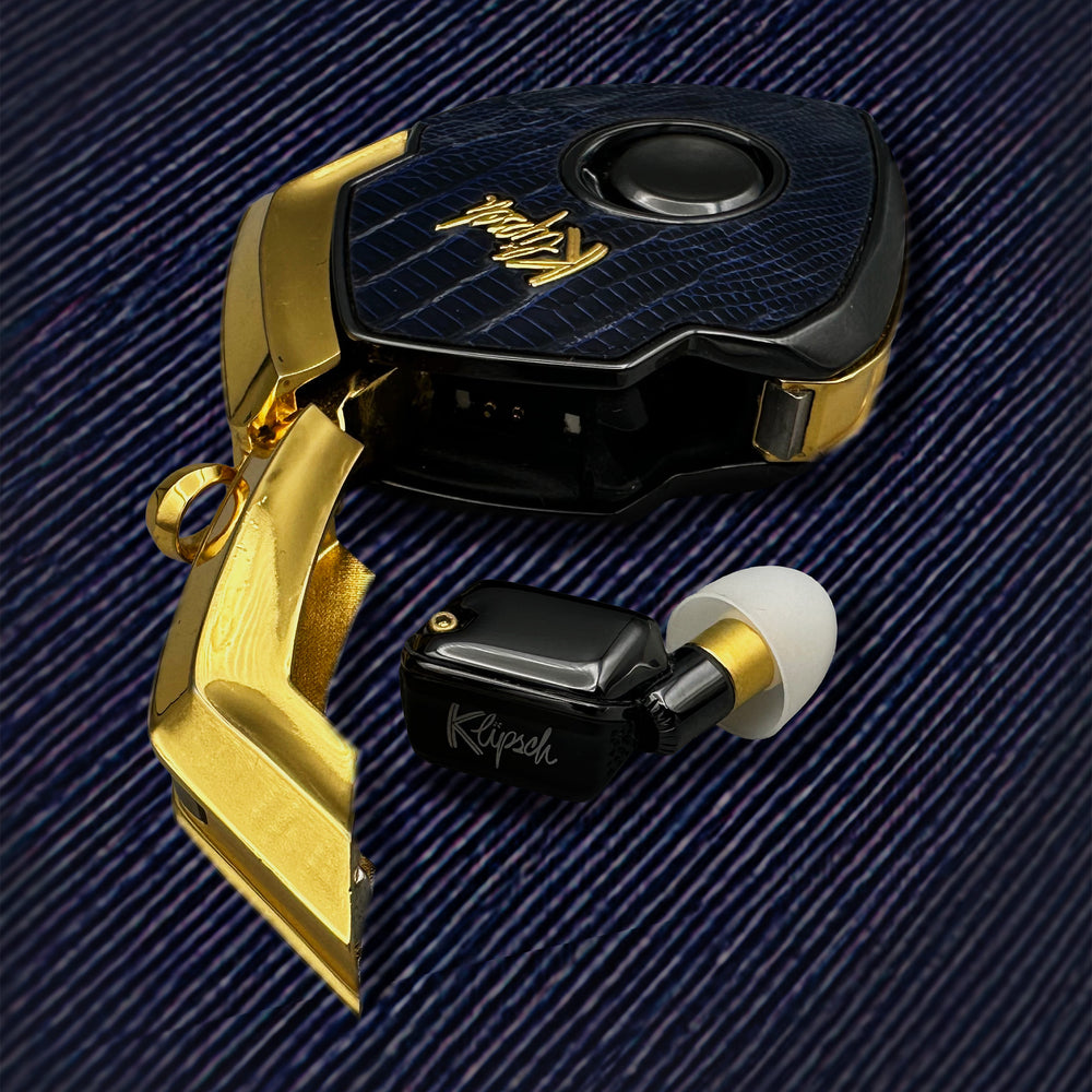 Aureate Navy charging case with navy lizard cover and gold door open beside a black earbud