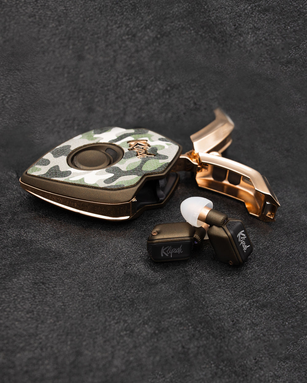Impractical Tactical charging case with camouflage cover and bronze doors open beside bronze earbuds