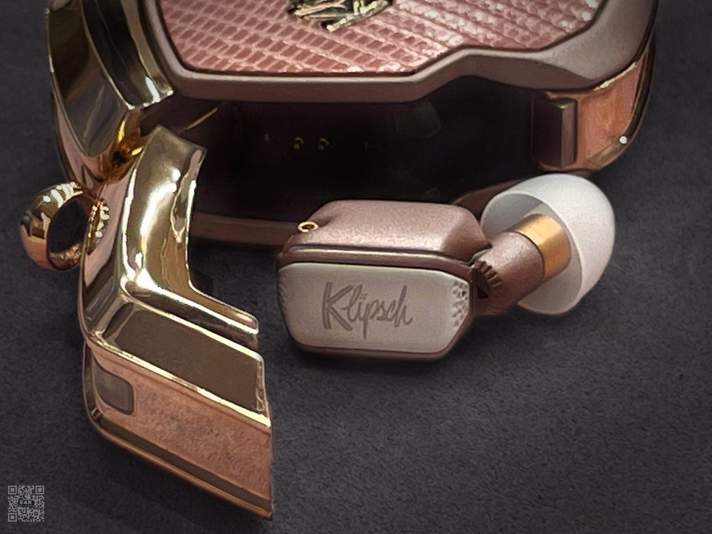 Desert Rose charging case with pink lizard cover and rose gold door open beside an earbud