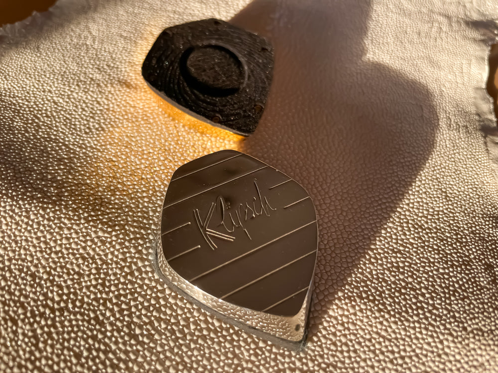 ICS Pocket Charging Base in black beside the polished metal version with engraved Klipsch logo